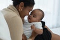 Happy African American family, young mother holding cute newborn baby girl in Arms with care smiling and sitting on bed at bedroom Royalty Free Stock Photo