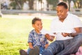 Happy African American Father and Mixed Race Son Playing with Paper Airplanes in the Park Royalty Free Stock Photo
