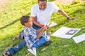 Happy African American Father and Mixed Race Son Making Paper Airplanes in the Park Royalty Free Stock Photo