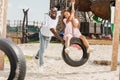 happy african american father pushing daughter on tire swing