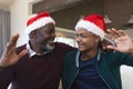 Happy african american father and son in christmas hats having video call and waving Royalty Free Stock Photo