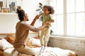 Happy african american father and son jumping on bed and laughing while playing together at home Royalty Free Stock Photo