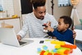 Happy african american father and son using laptop while playing Royalty Free Stock Photo