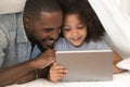 Happy african american father using digital tablet with cute daughter. Royalty Free Stock Photo