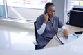 Happy african american female doctor talking on phone in hospital reception Royalty Free Stock Photo