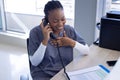 Happy african american female doctor talking on phone in hospital reception Royalty Free Stock Photo