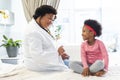 Happy african american female doctor talking to girl patient at hospital Royalty Free Stock Photo