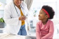Happy african american female doctor talking to girl patient at hospital Royalty Free Stock Photo