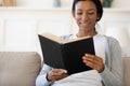 Happy African American female reading book at home Royalty Free Stock Photo