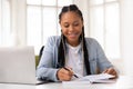 Happy african american female teen studying with laptop and notebook at home Royalty Free Stock Photo