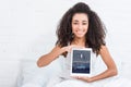 Happy african american girl showing digital tablet with tumblr on screen in bed