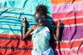 Happy african american girl in sunglasses showing peace sign while lying on towels at beach