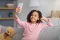 Happy teenage girl taking selfie for social network, holding smartphone in hand, shooting at home Royalty Free Stock Photo