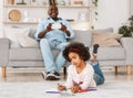 Happy African American granddad taking picture of his granddaughter drawing on floor Royalty Free Stock Photo