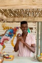 Happy african american male bartender preparing cocktail with shaker behind the counter at beach bar Royalty Free Stock Photo