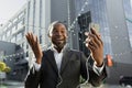 Happy African American male businessman talking to his team via video call. Standing outside an office center wearing Royalty Free Stock Photo