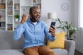 Joyful man celebrating success with smartphone at home Royalty Free Stock Photo