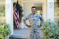 Happy african american male soldier with hands on hips outside home with usa flag, copy space Royalty Free Stock Photo