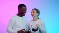 Happy African-American man and caucasian woman in white clothes remove vr goggles and laugh