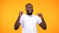 Happy african american man dancing on yellow background, celebrating success