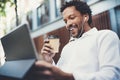 Happy African American man in earphones making video call via electronic touch pad with take away coffee in hand.Concept