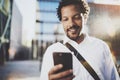 Happy African American man in headphone walking at sunny city and enjoying to listen to music on his smart phone.Blurred Royalty Free Stock Photo