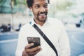 Happy African American man in headphone walking at sunny city and enjoying to music on his smartphone.Concept of guy Royalty Free Stock Photo