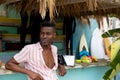 Happy african american man leaning on counter at surf hire beach shack, copy space Royalty Free Stock Photo