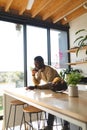 Happy african american man leaning on countertop and talking on smartphone in kitchen Royalty Free Stock Photo