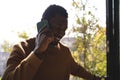 Happy african american man looking through window and talking on smartphone Royalty Free Stock Photo