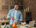 Happy african-american man preparing salad in kitchen Royalty Free Stock Photo