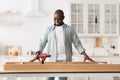 Happy african american man ready to installing wooden desk after home relocation, looking at new table