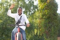 A happy African-American man rides a bicycle in the park