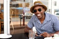 Happy african american man sitting at cafe with mobile phone Royalty Free Stock Photo