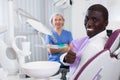 Happy african american man sitting in dental chair after teeth cure giving thumb up Royalty Free Stock Photo