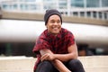 Happy african american man sitting outside in city and smiling Royalty Free Stock Photo