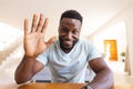 Happy african american man sitting at table and having video call, waving to camera Royalty Free Stock Photo