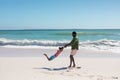 Happy african american man spinning daughter at beach while enjoying summer holiday together Royalty Free Stock Photo