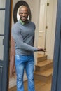 Happy african american man standing in doorway, smiling and inviting in