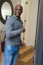 Happy african american man standing in doorway, smiling and inviting in