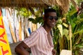 Happy african american man in sunglasses leaning on counter at surf hire beach shack Royalty Free Stock Photo