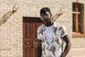 Happy African American man in sunglasses stands near a brick building on the street on a sunny day. Close-up portrait Royalty Free Stock Photo