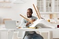 Happy african american man twisting part in chair and looking at laptop, watching online video instructions in kitchen Royalty Free Stock Photo