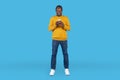 Happy african american man using cell phone isolated on blue Royalty Free Stock Photo