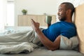 African American Man Using Cellphone Drinking Coffee Lying In Bedroom Royalty Free Stock Photo