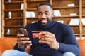 Happy African-American man using a smartphone for online shopping Royalty Free Stock Photo