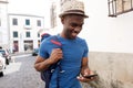 Happy african american man walking outdoors in the city with cellphone and bag Royalty Free Stock Photo