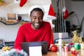 Happy african american man wearing santa hat, using tablet for video call Royalty Free Stock Photo