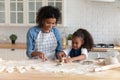 Happy African American mom helping cute daughter to bake biscuit Royalty Free Stock Photo