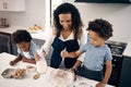 Happy african american mother baking with her sons. Two brothers baking with their parent in the kitchen at home. Little Royalty Free Stock Photo
